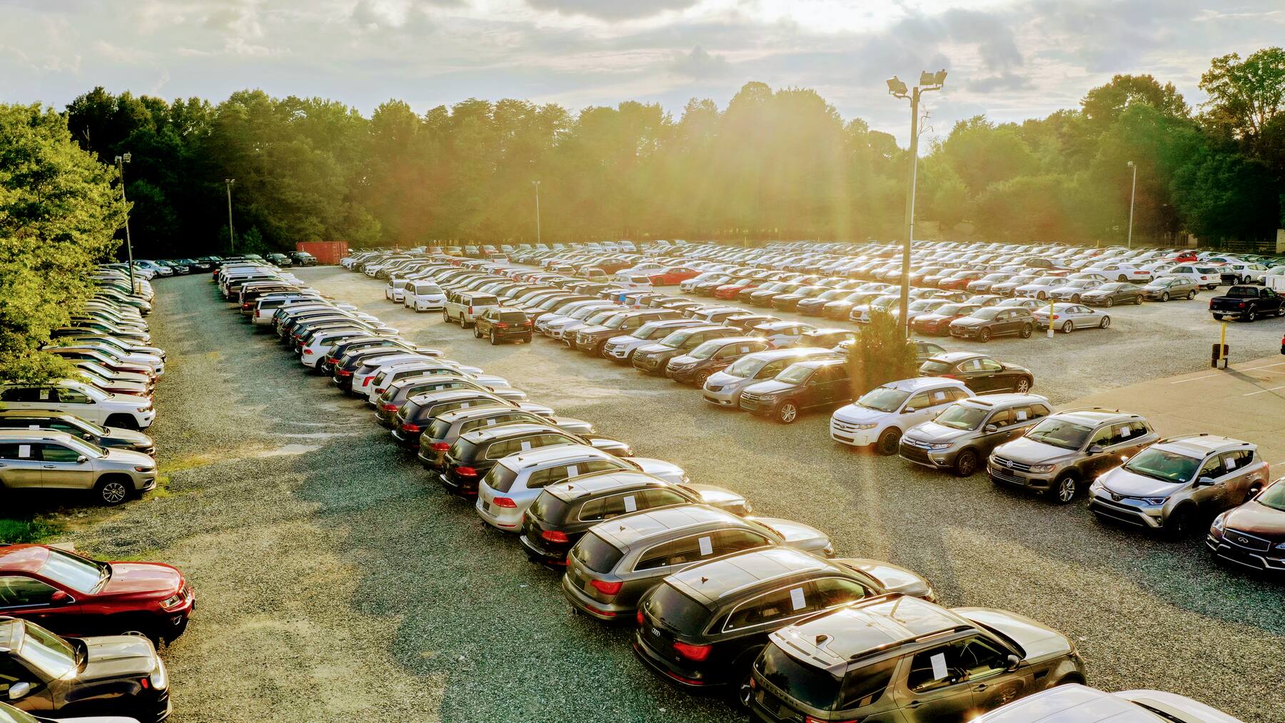 Hundreds of used cars, trucks and SUVs lined up on the Impex Auto Sales lot in Greensboro at sunset