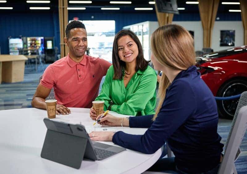 An Impex Auto Sales associate going over a purchase with two customers in the Greensboro showroom